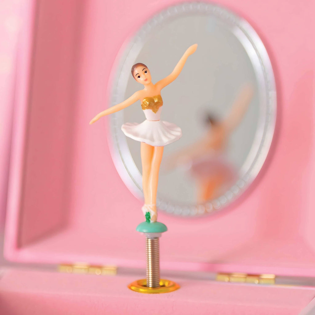 White ballerina with white tutu and gold trim that spins and plays a song from swan lake behind a mirror with pink background and gold hardware.