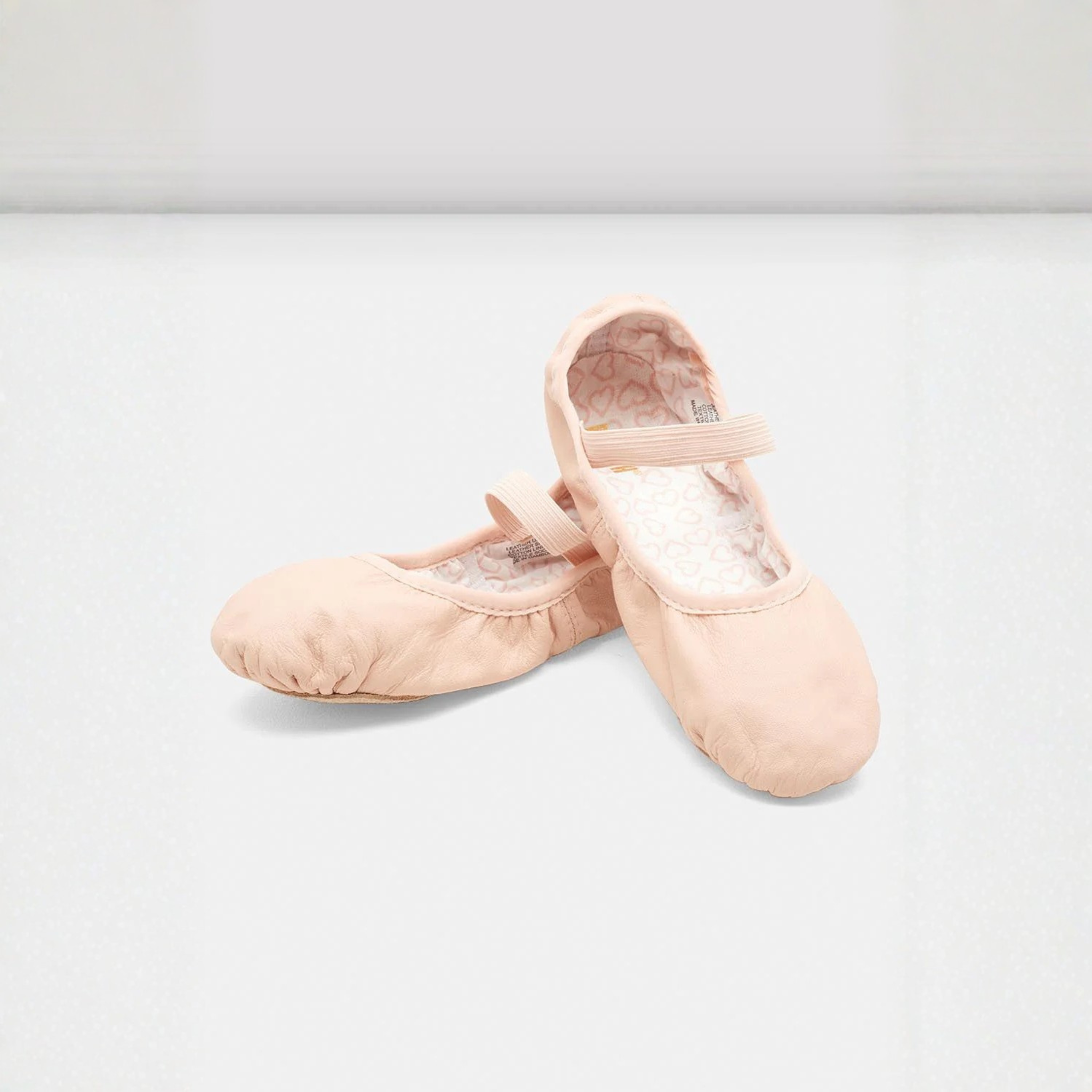 Bloch S0227G Children Belle Leather Ballet Shoe Side, Front, and Inside View. The inside displays a white fabric with pink small hearts throughout. In addition, this style is full sole and has one elastic strap.