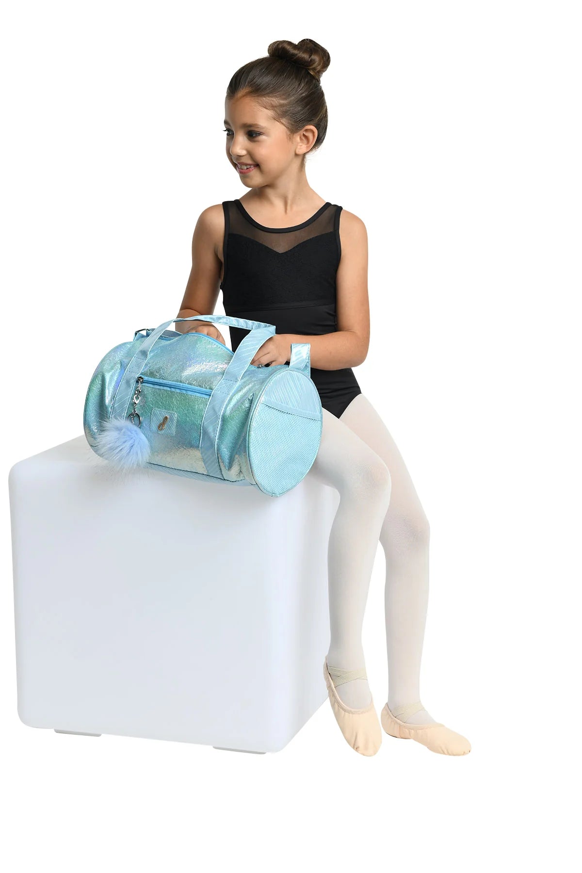 Girl holding Danz N Motion blue iridescent duffel bag with a pom-pom charm and side mesh pocket.