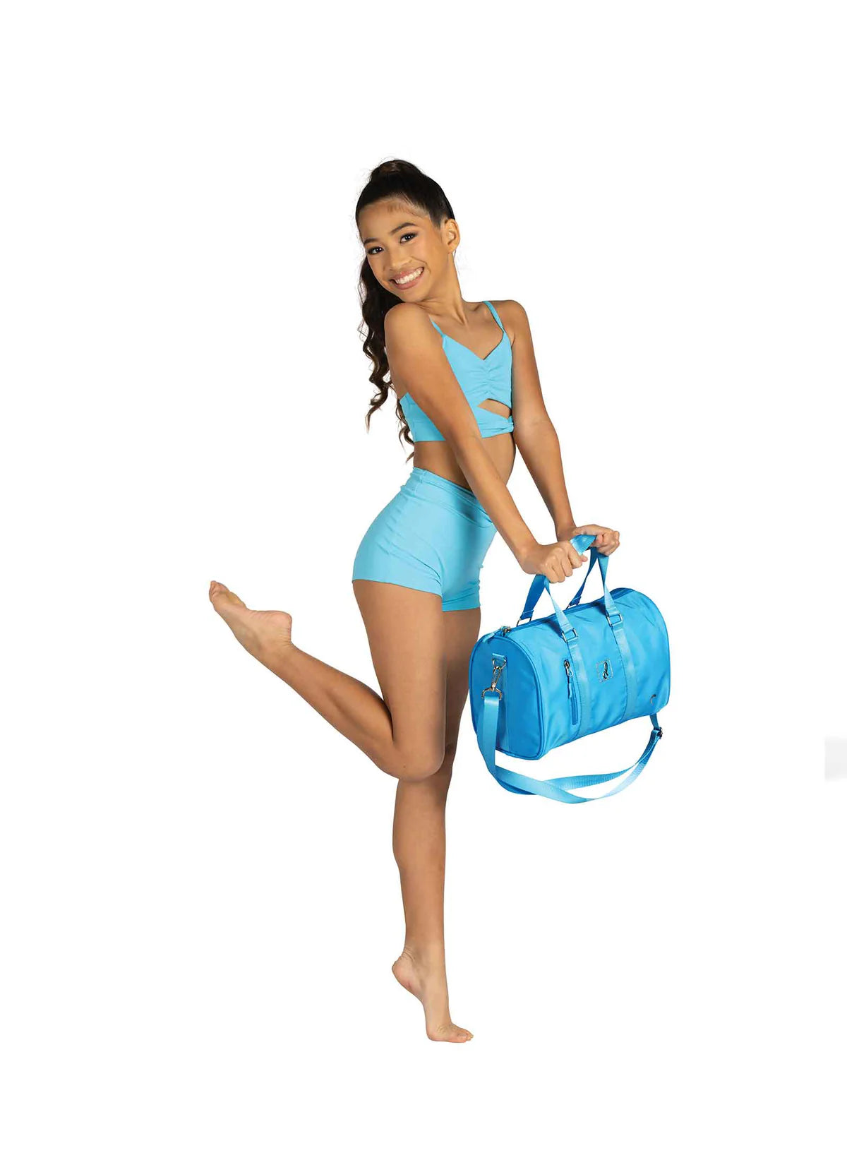 Woman in blue athletic wear holding a matching blue duffel bag on a white background