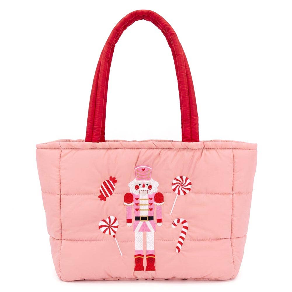 Faire Nutcracker Holiday Candy Cane Embroidered Quilted Shoulder Tote Bag. It has a red strap, the bag is pink with nutcracker, candy cane, lollypops, and candy on it.
